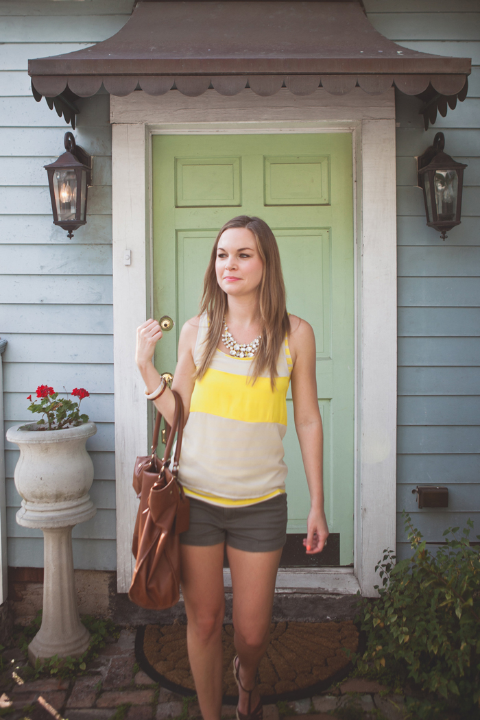 Ciera wearing olive shorts, yellow top and brown leather bag